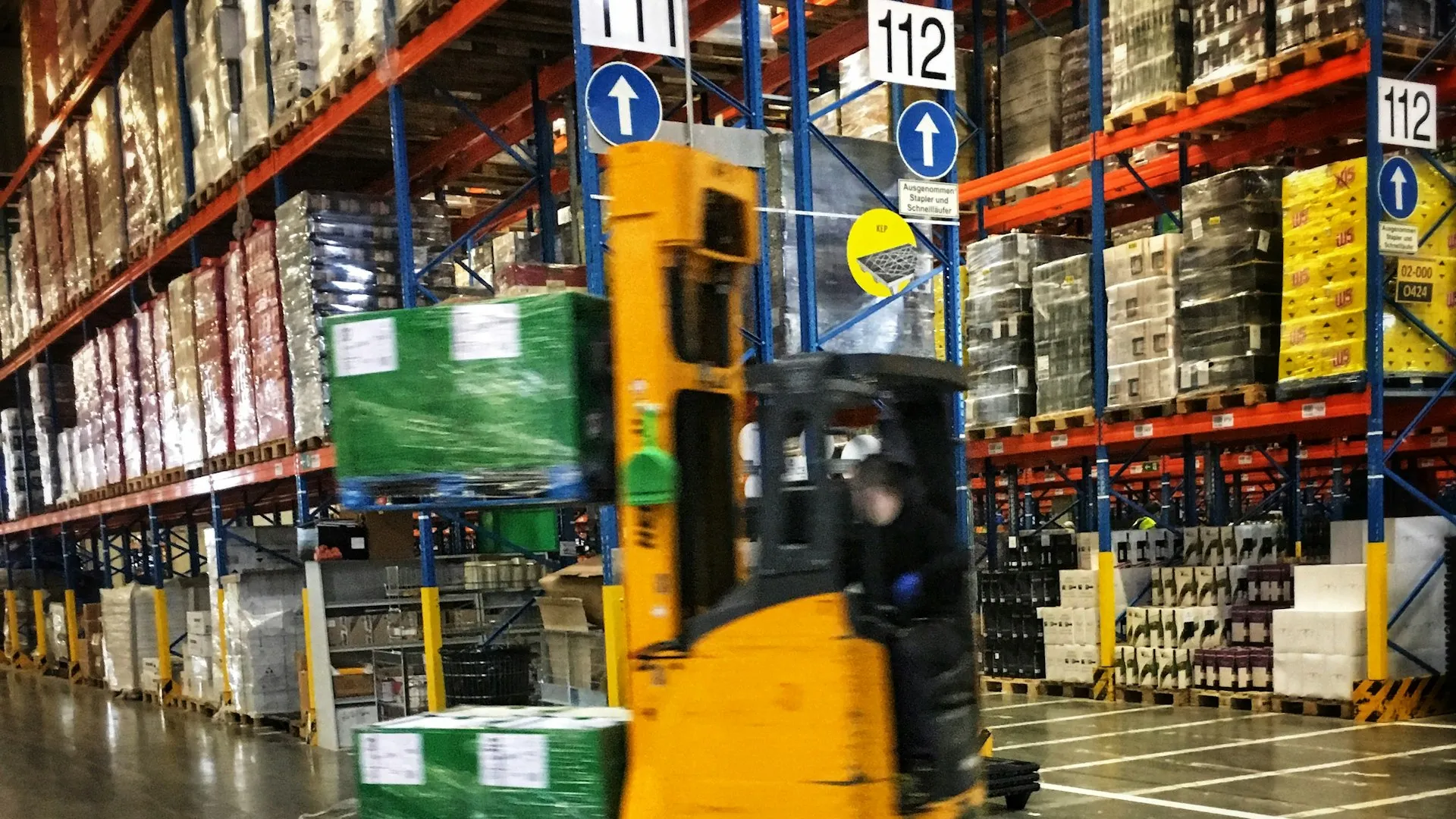 Vysokozdvižný vozík v sklade s regálmi plnými paliet
