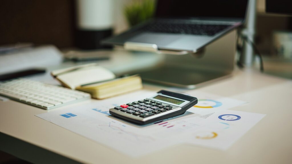 Kalkulačka a finančné prehľady na pracovnom stole s notebookom