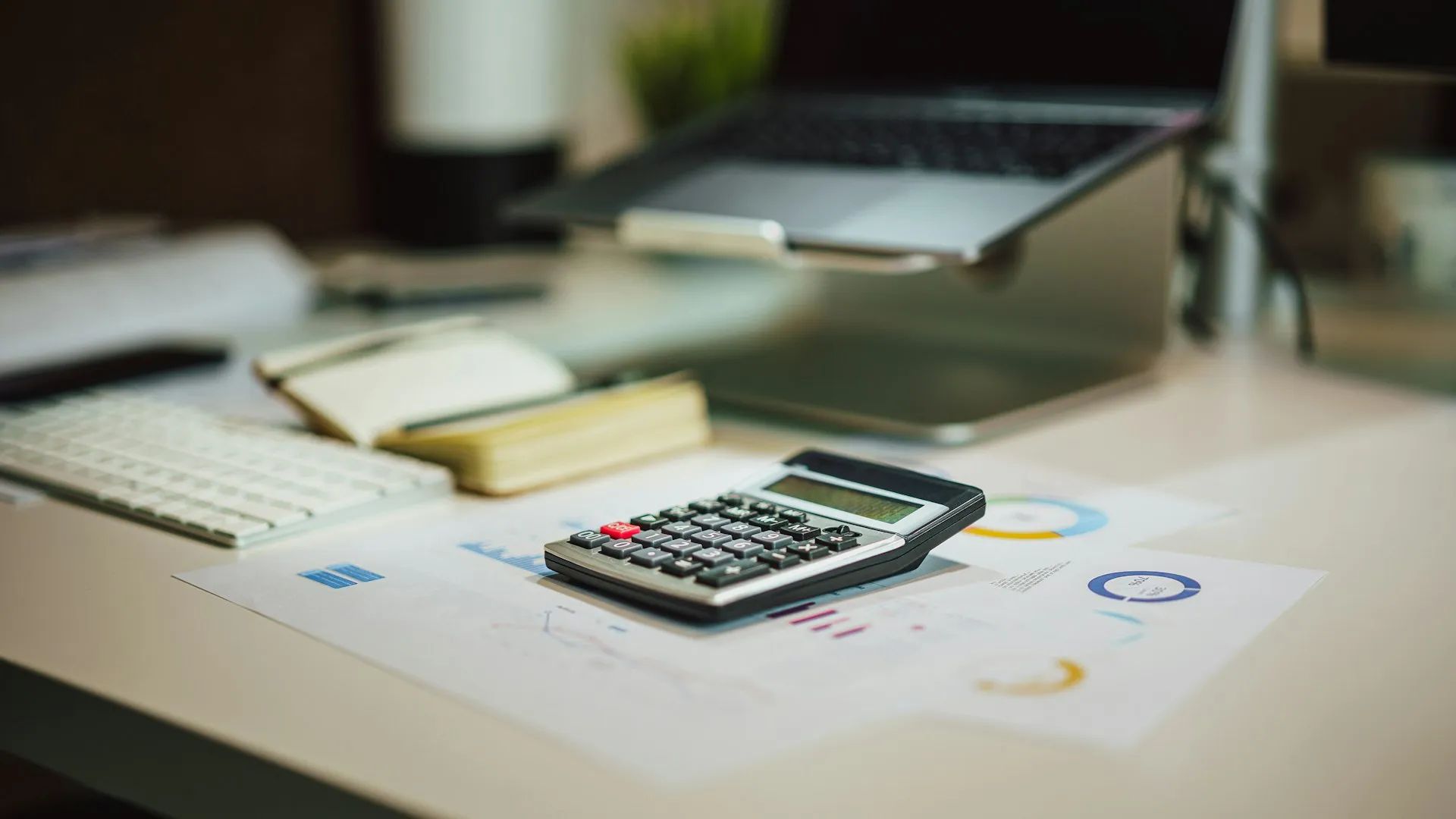 Kalkulačka a finančné prehľady na pracovnom stole s notebookom
